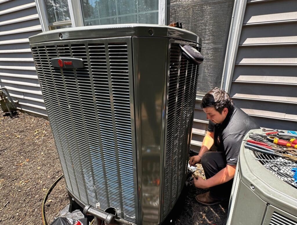 A SwiftPro technician performing an air conditioning tune-up on an outdoor condenser unit at a Northern Virginia home