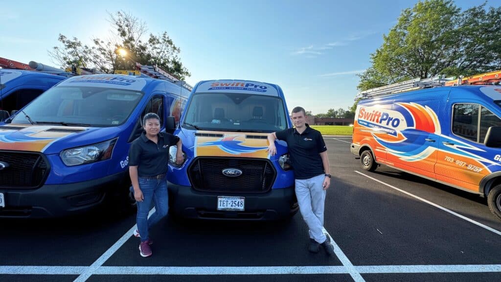 Two SwiftPro technicians standing in front of the SwiftPro van fleet in Northern Virginia