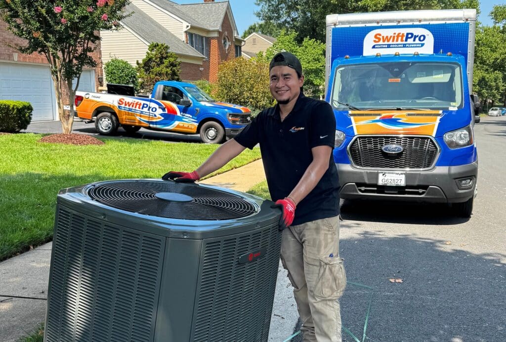 A SwiftPro technician installing a new Trane air conditioning system at a Northern Virginia home, with two branded SwiftPro trucks parked in the driveway