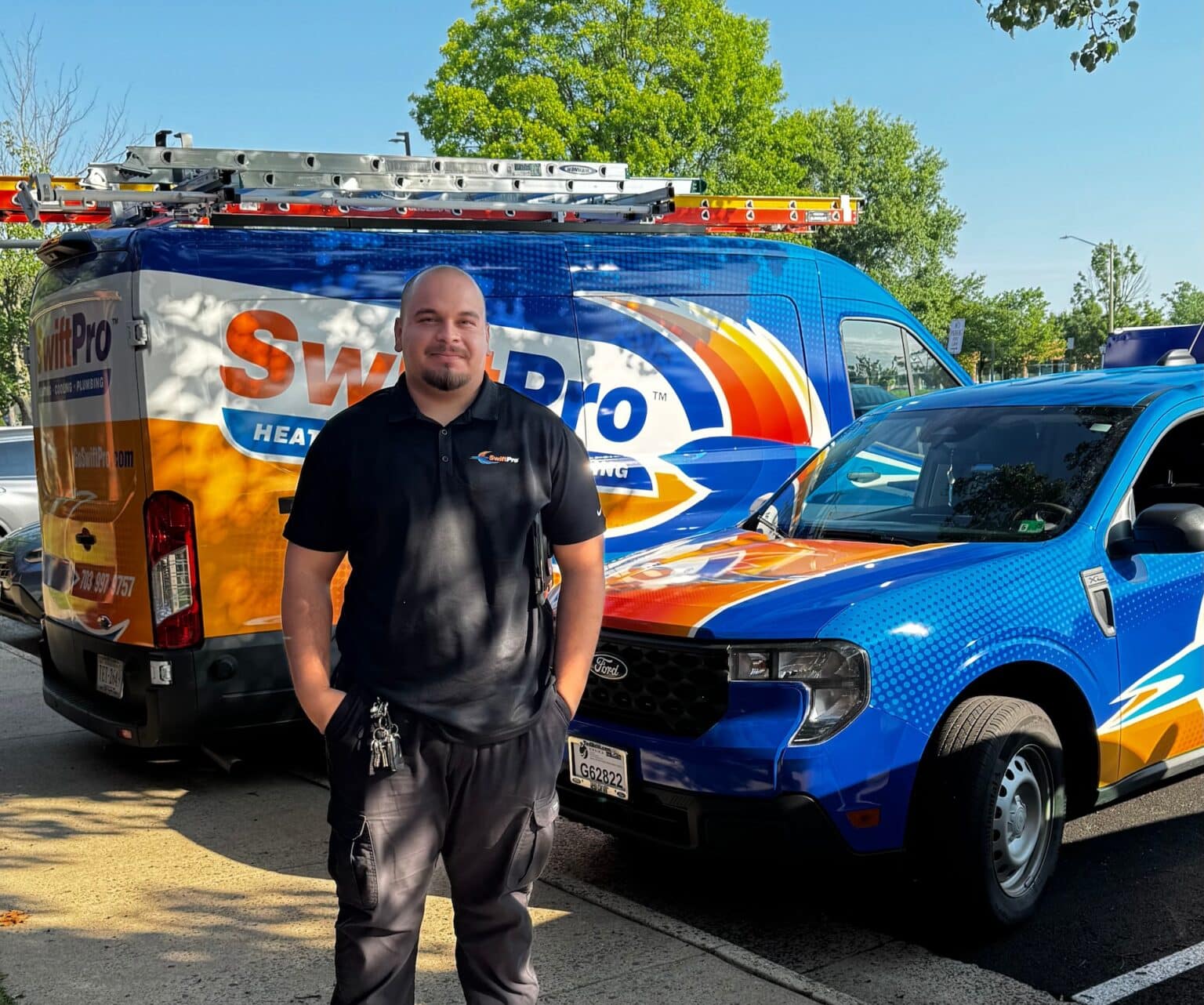 A SwiftPro technician standing in front of a wrapped SwiftPro van and a matching blue SwiftPro pickup in Northern Virginia