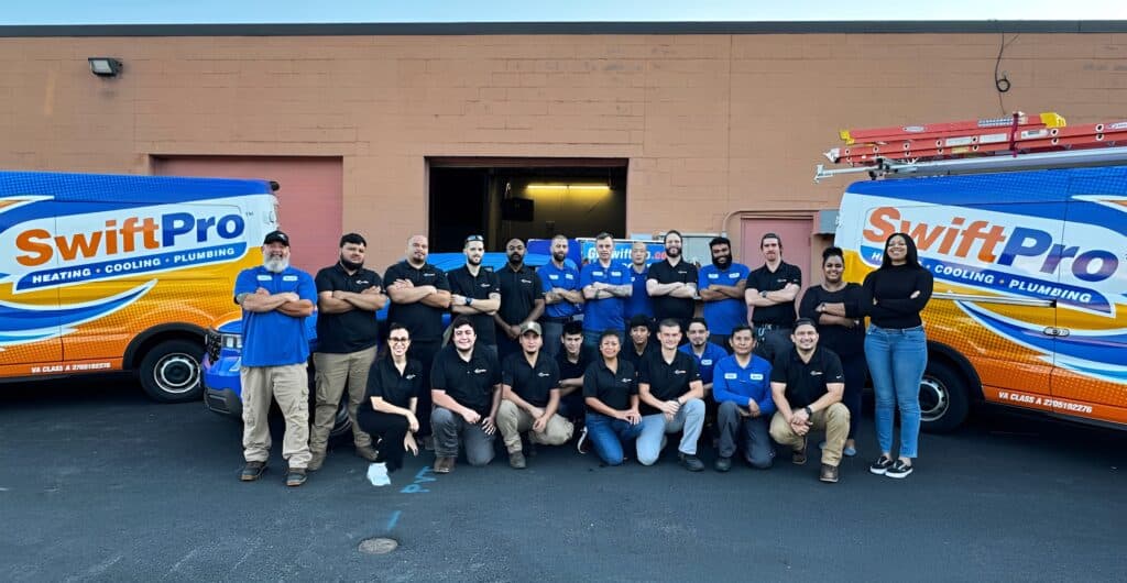 SwiftPro team in Northern Virginia, HVAC and plumbing specialists, standing in front of company vehicles.
