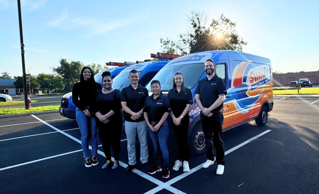 A Northern Virginia heating, cooling and plumbing crew standing in front of three wrapped service vans