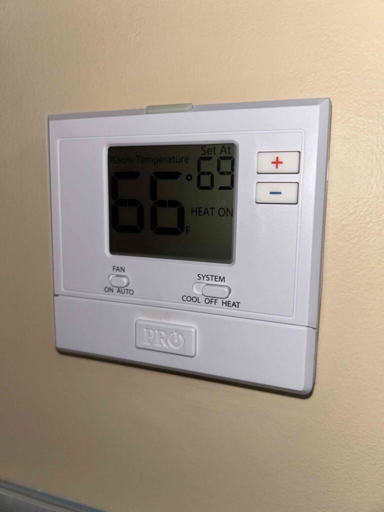 HVAC thermostat displaying 66 degrees, illustrating temperature control and energy savings.