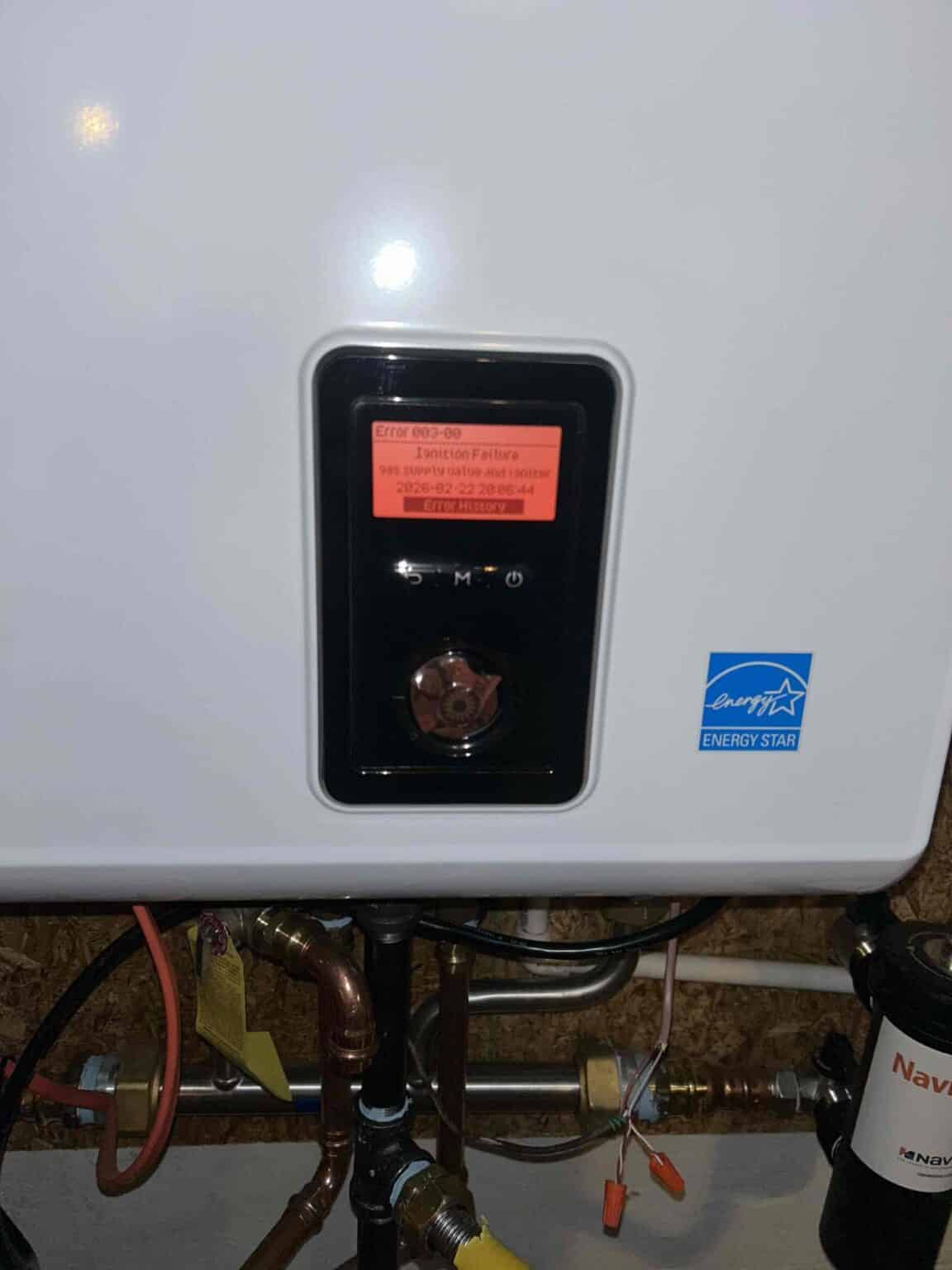 A SwiftPro technician checking the gas control valve and status light on a tank water heater in a Northern Virginia home