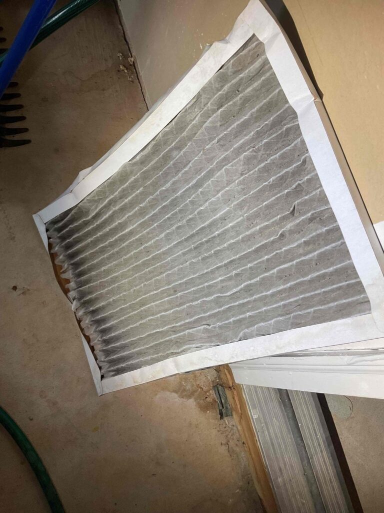 A return air filter pulled from a Northern Virginia HVAC system, grey and loaded with dust.