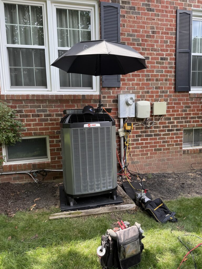 An outdoor condenser at a Northern Virginia home with an umbrella shading it and service tools laid out