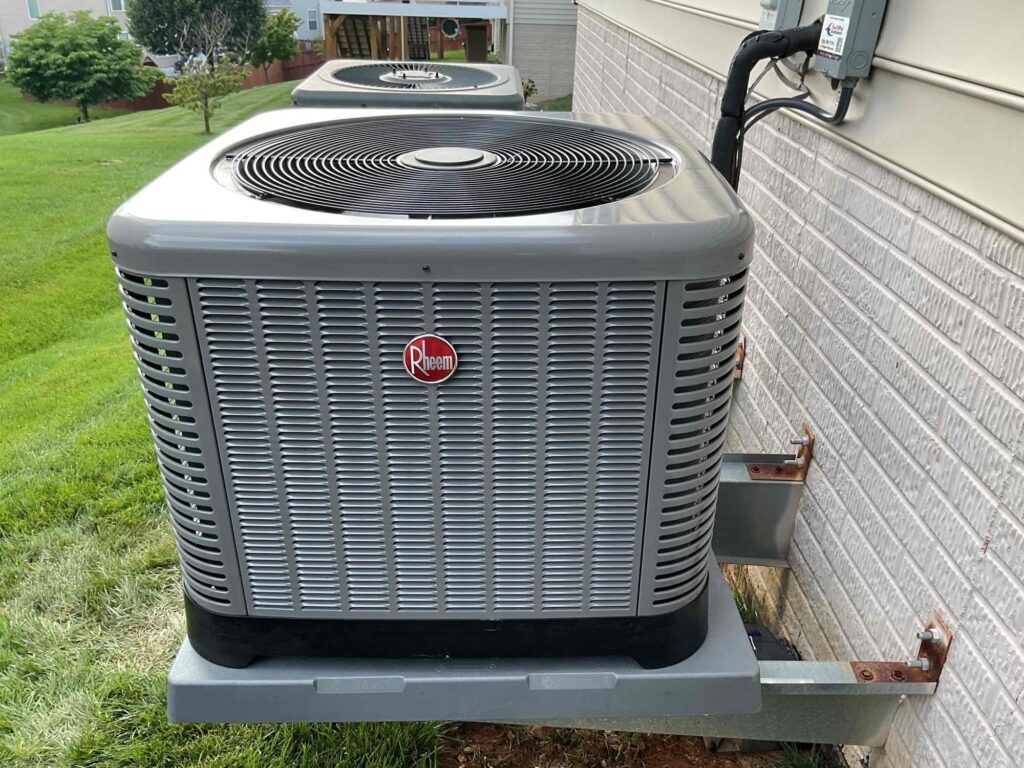 A Rheem condenser installed by SwiftPro on a bracket beside a brick Northern Virginia home