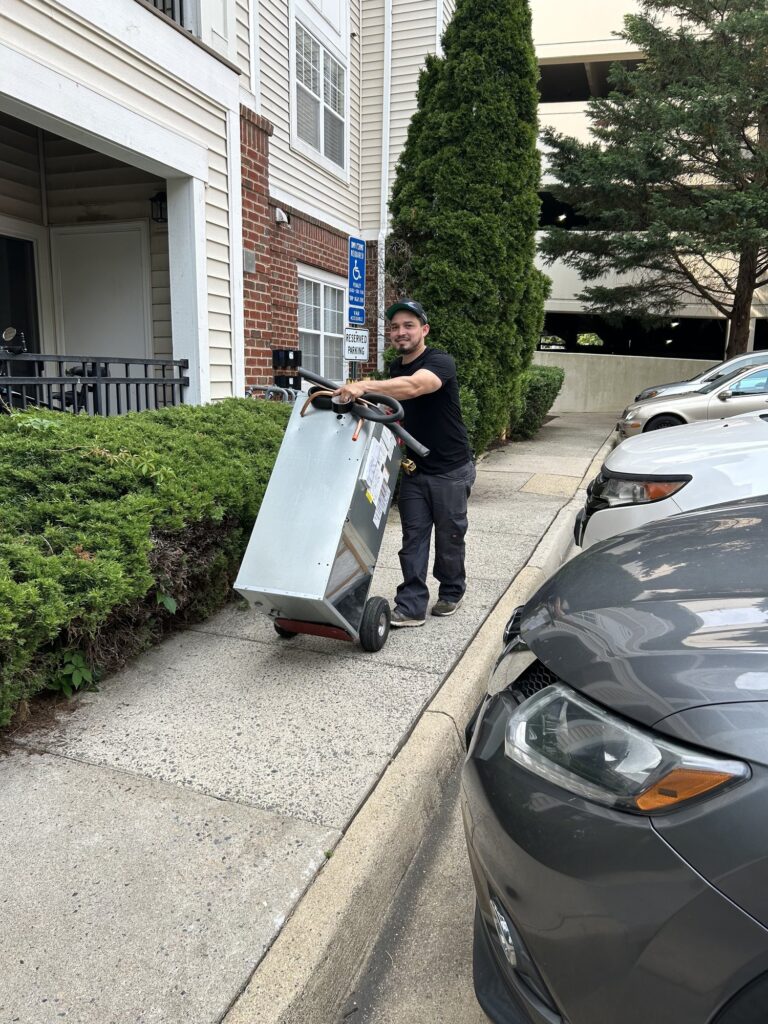 A SwiftPro technician wheeling new equipment on a hand truck up a Northern Virginia driveway.