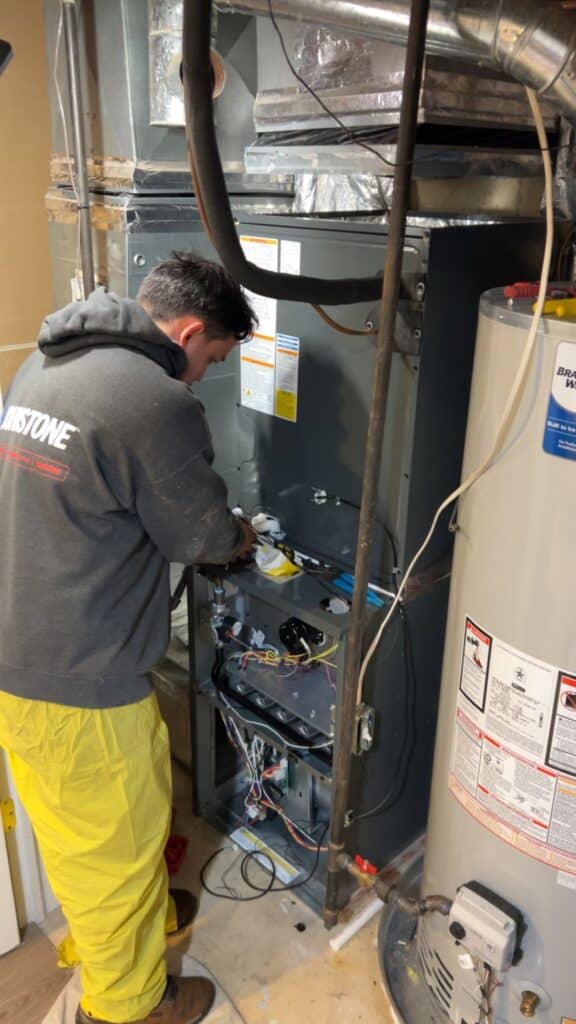 A SwiftPro technician working on the gas control valve of a tank water heater in Northern Virginia.