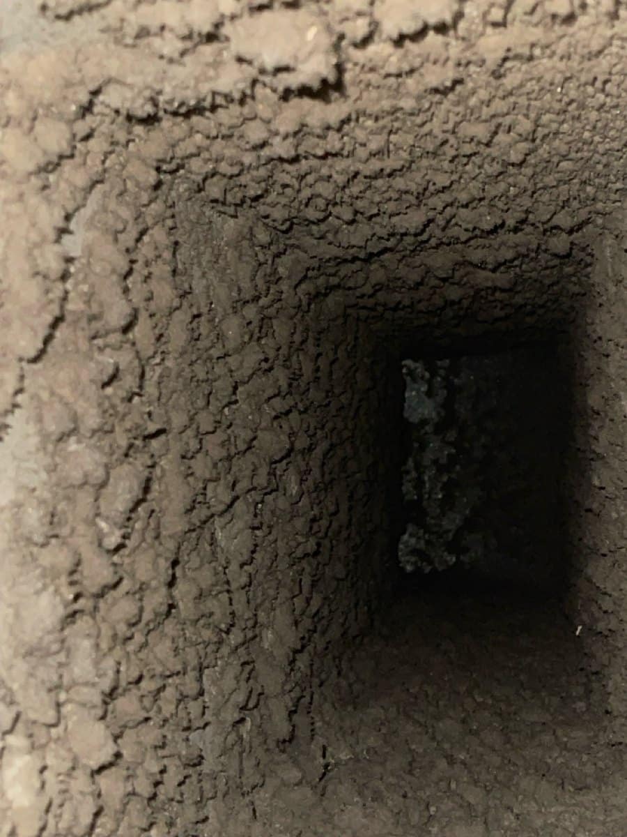 Inside a Northern Virginia supply duct before a SwiftPro cleaning, the sheet metal coated in thick grey dust
