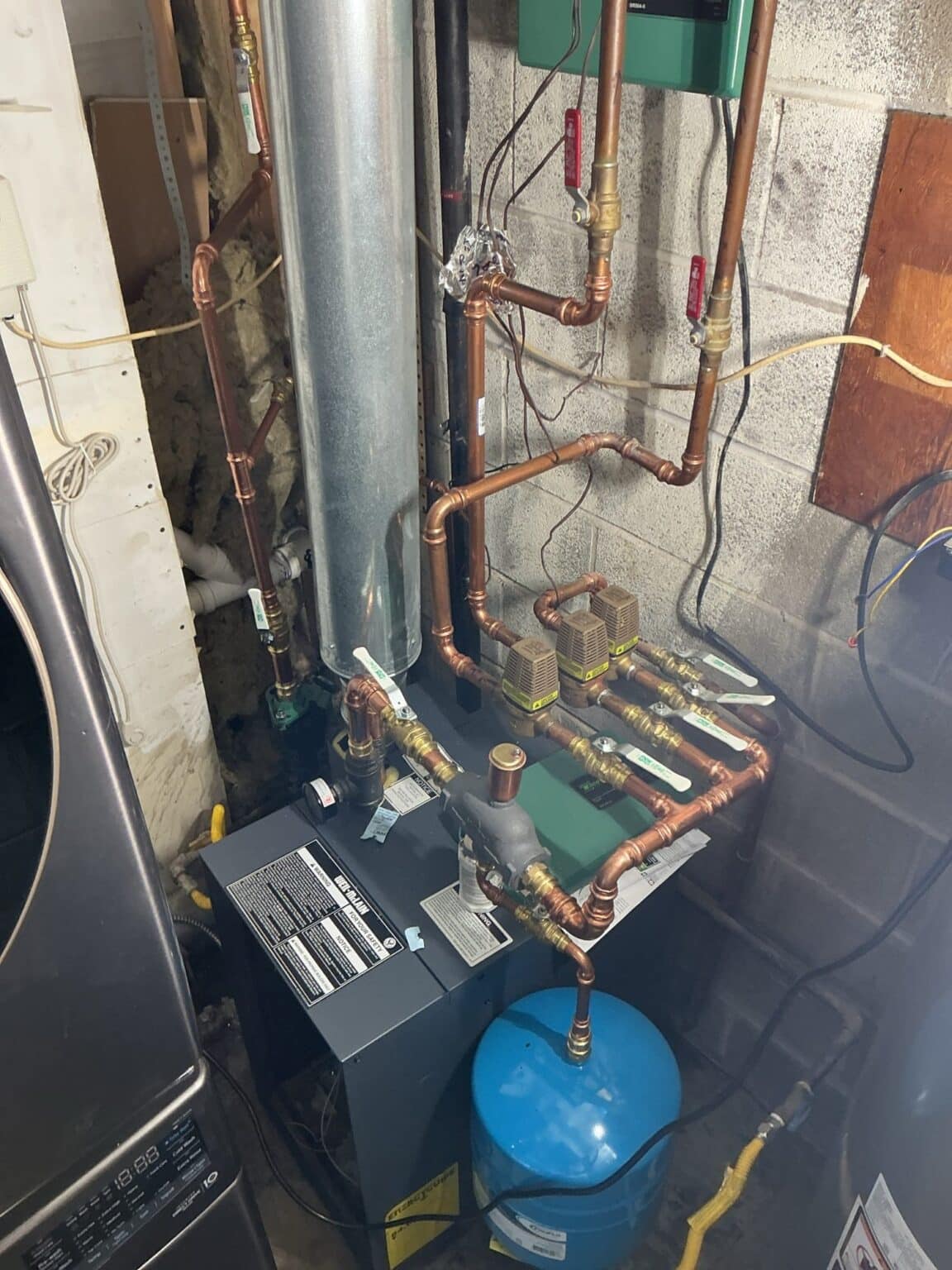 A new Weil-McLain cast iron gas boiler SwiftPro installed on the chimney in a Northern Virginia basement, with rebuilt copper piping and a blue expansion tank