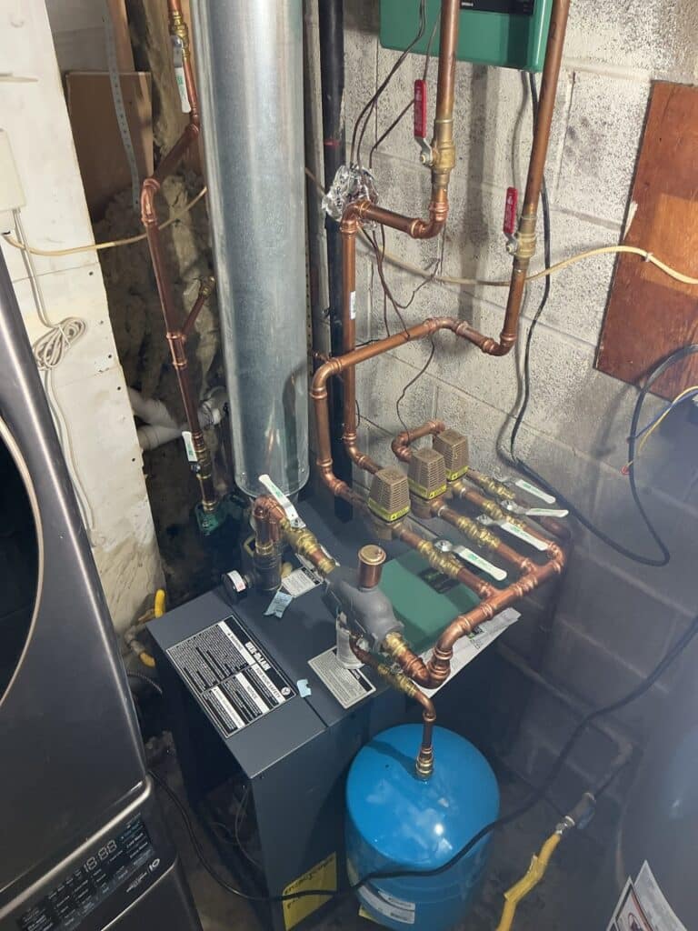 A SwiftPro boiler installation in a Northern Virginia utility room showing the new flue, the blue expansion tank and the rebuilt copper near-boiler piping