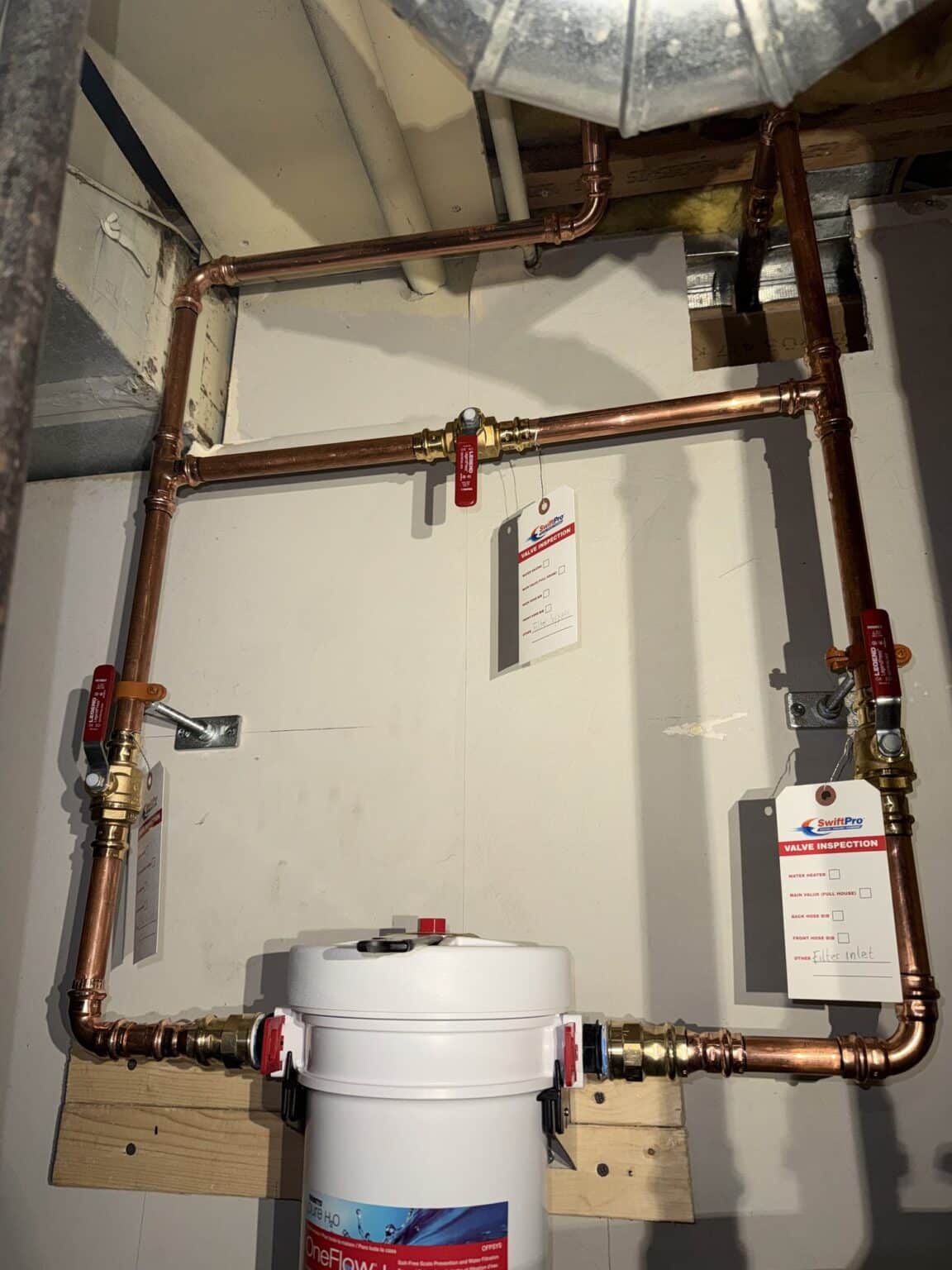A rebuilt copper plumbing manifold with a whole-house water filter installed by SwiftPro in a Northern Virginia basement