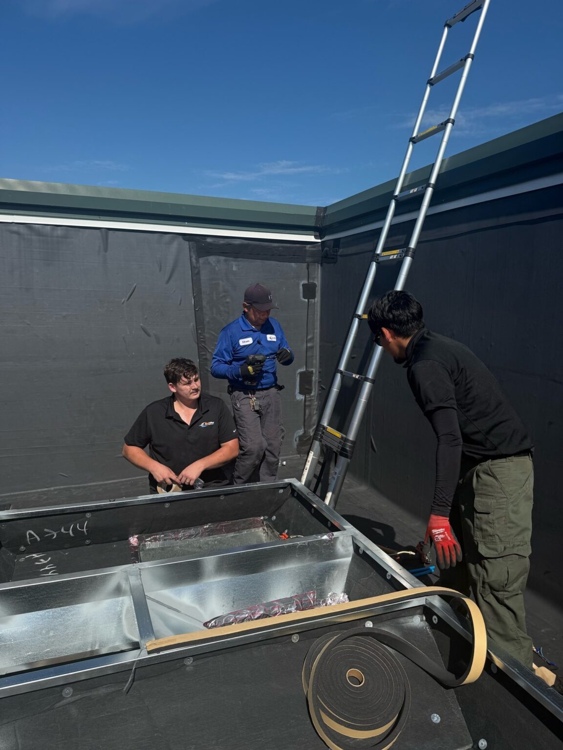 Three SwiftPro technicians on a church roof in Chantilly, Virginia, fitting the curb adapter for a new rooftop HVAC unit