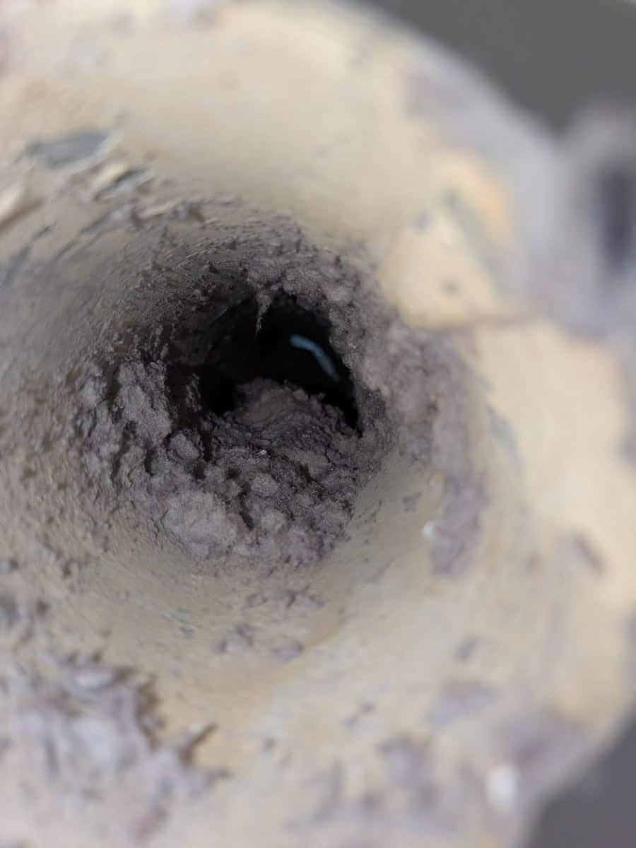Inside a dryer vent line packed with grey lint before cleaning, Ashburn, Virginia
