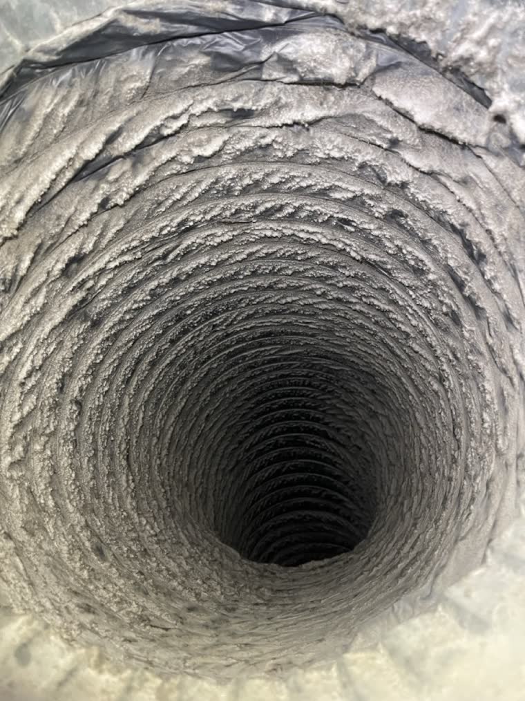 The inside of a flexible round duct in a Northern Virginia home before cleaning, grey lint packed into every corrugation