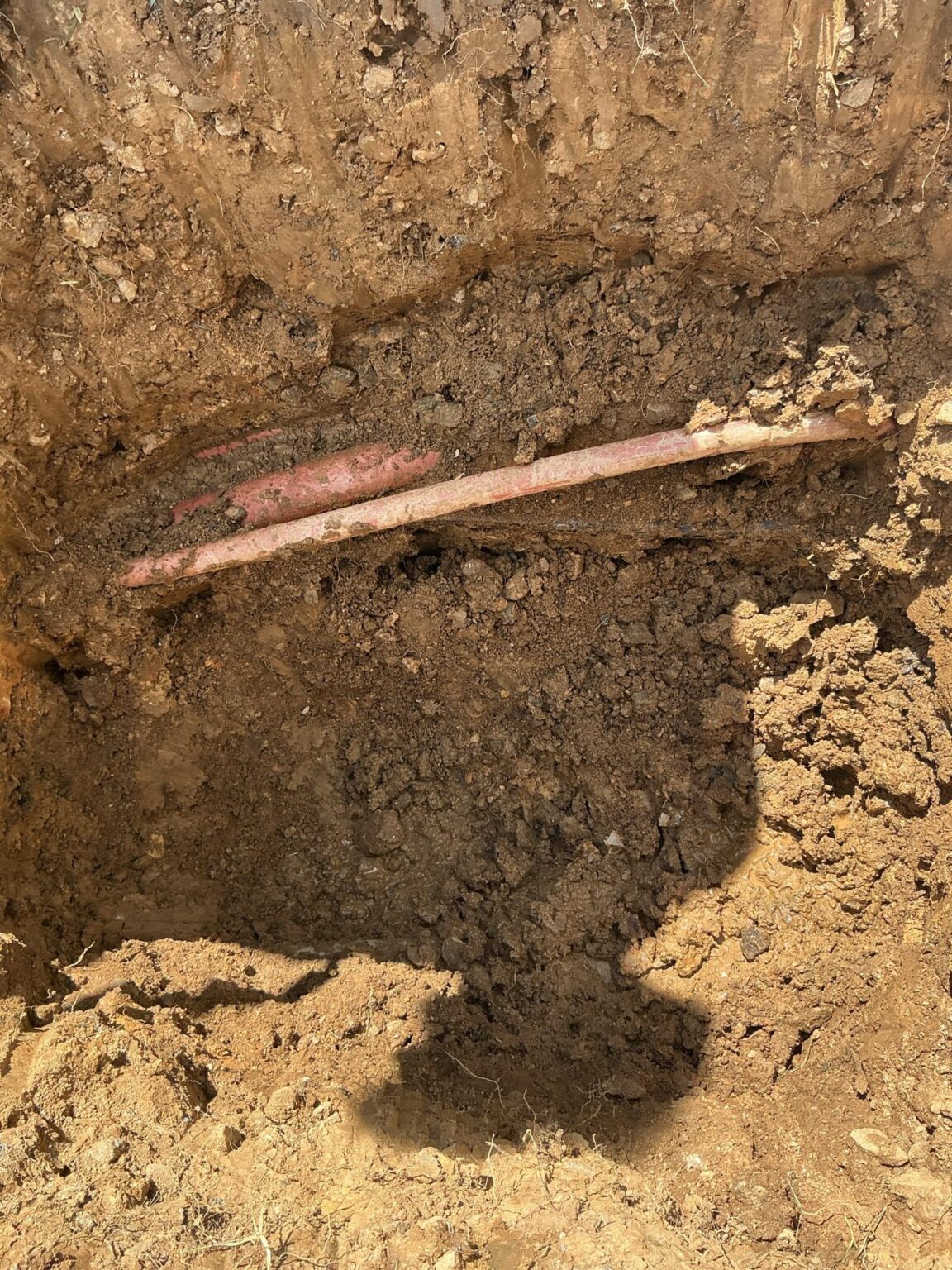 An excavated trench in a Northern Virginia yard exposing buried service pipes during a SwiftPro plumbing repair
