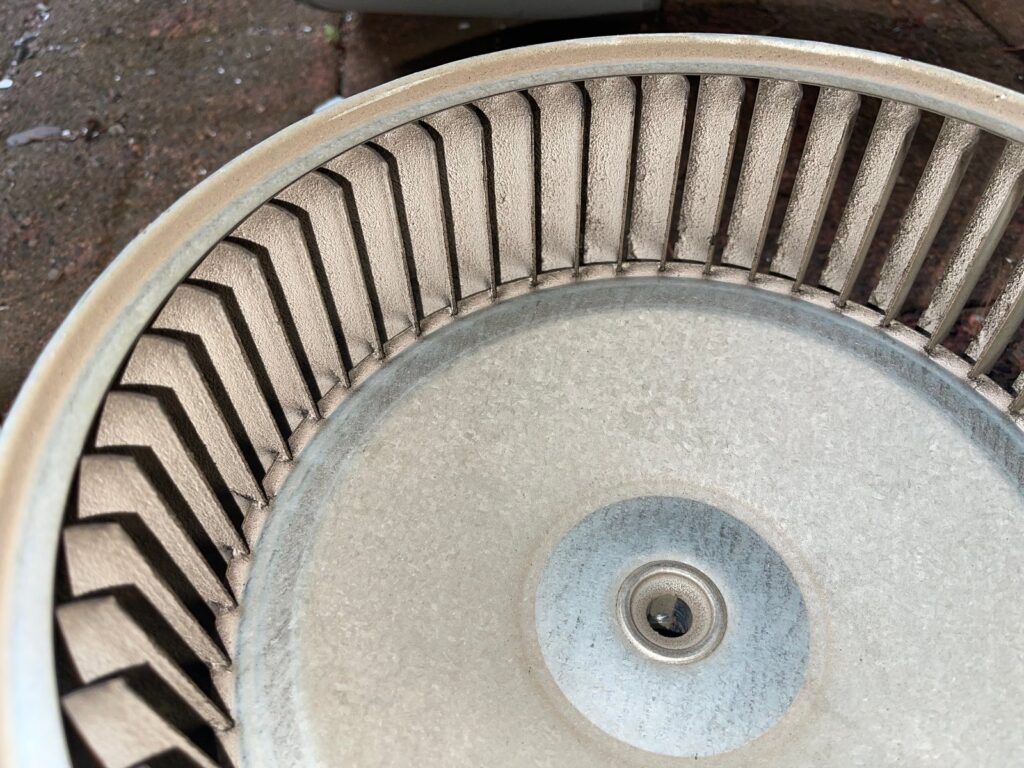Close-up of a furnace blower wheel pulled out on a SwiftPro heating job in Northern Virginia, with a coat of dust packed onto every blade