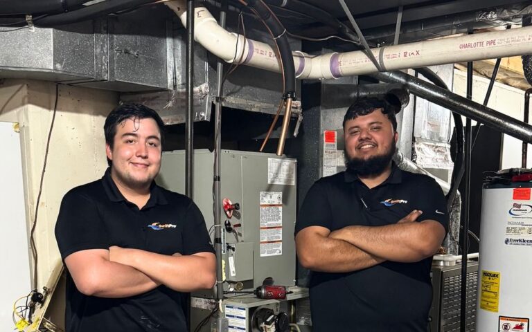 Two SwiftPro HVAC technicians in a Northern Virginia basement mechanical room, beside the furnace and water heater