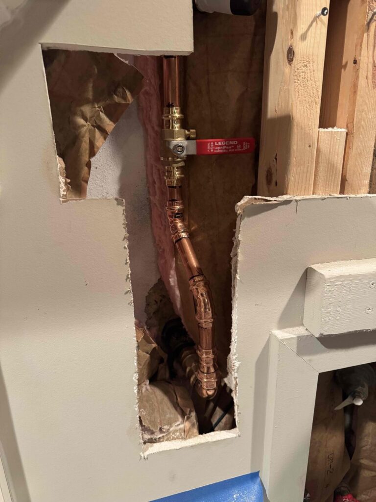An opened bathroom wall cavity in a Northern Virginia home exposing the copper supply piping SwiftPro repaired after a leak