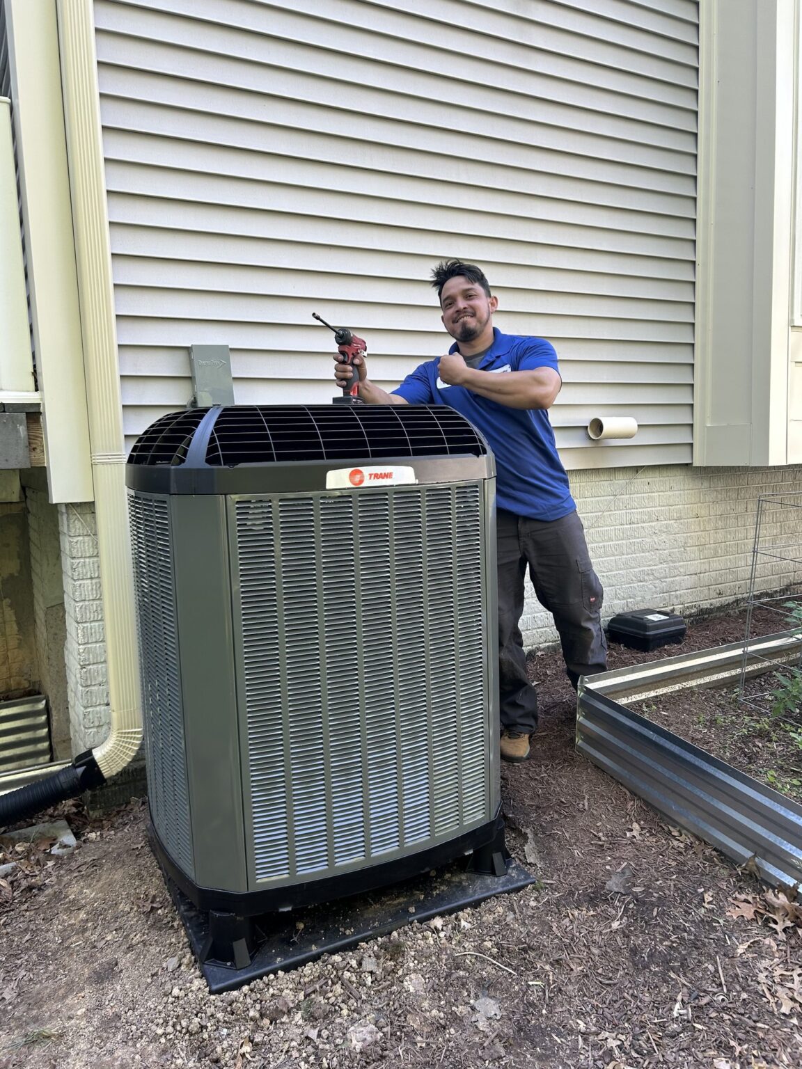 A SwiftPro technician standing beside a newly installed Trane air conditioning condenser at a Northern Virginia home