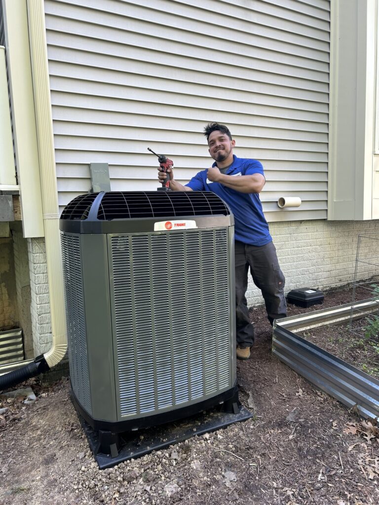 A SwiftPro technician standing beside a newly installed Trane air conditioning condenser at a Northern Virginia home