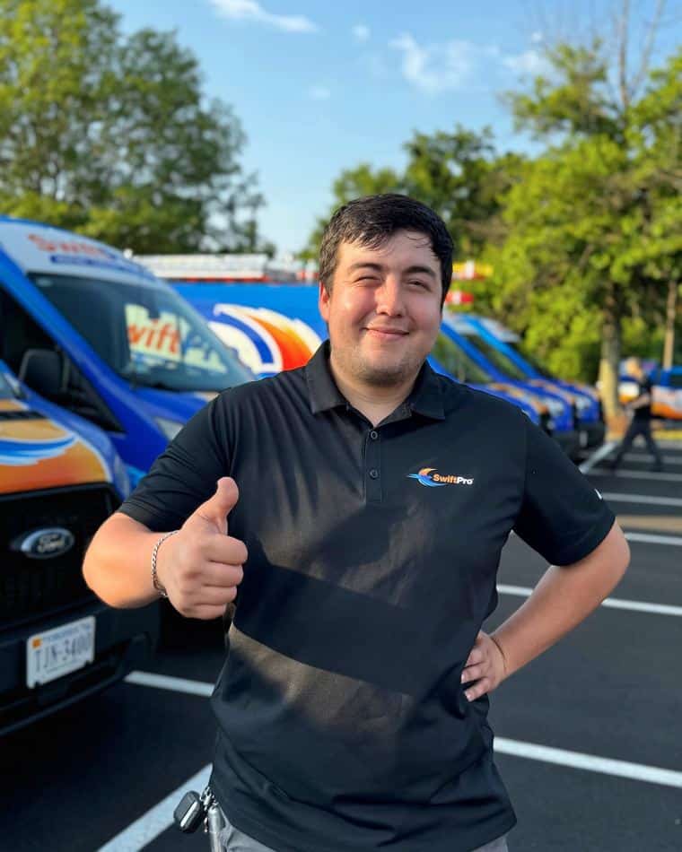 A SwiftPro technician giving a thumbs up in front of the SwiftPro vans