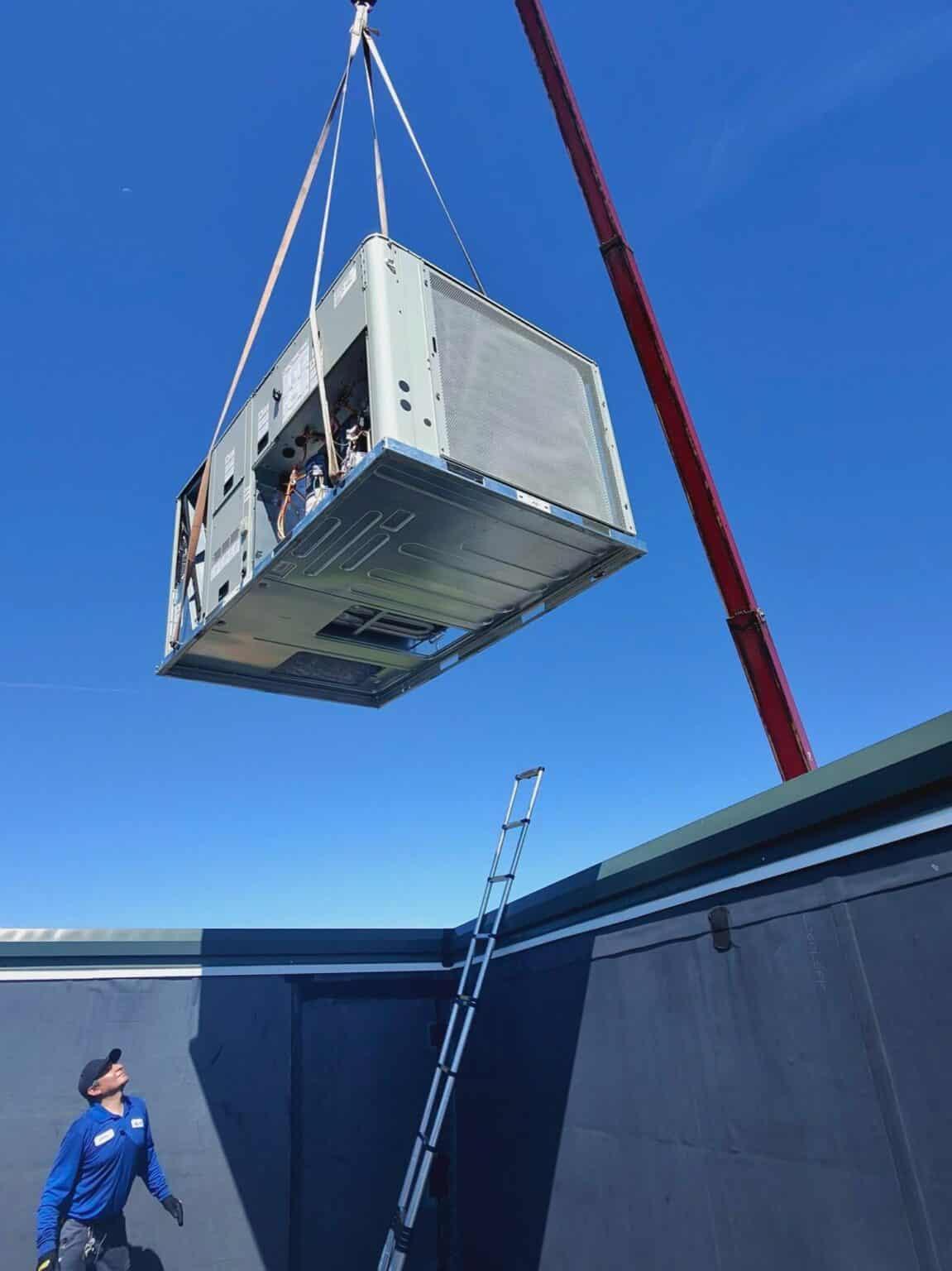 A SwiftPro HVAC technician on a church roof in Northern Virginia watching a new rooftop unit come up by crane