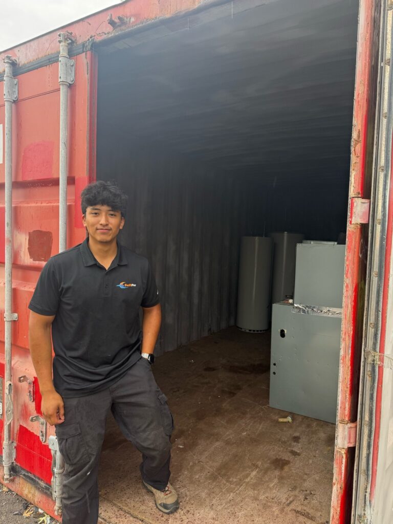 A SwiftPro technician standing in a storage container of new water heaters in Northern Virginia