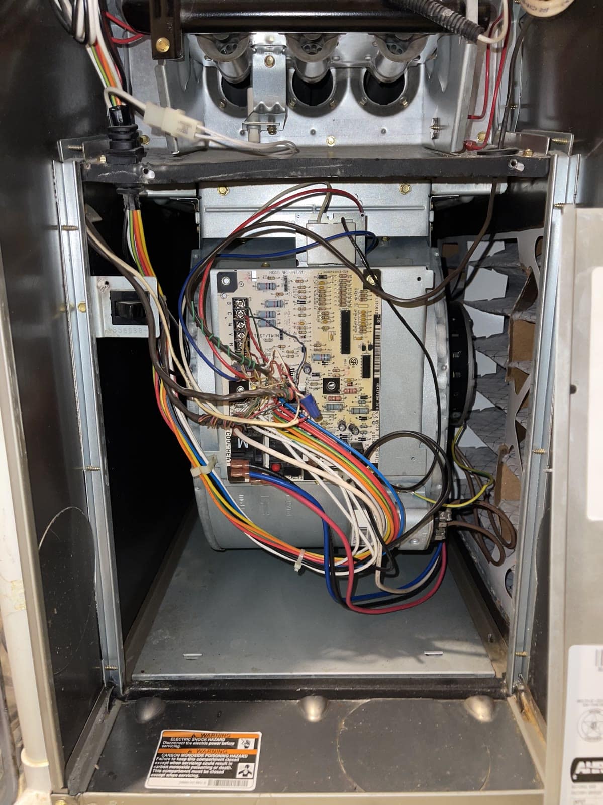 Open furnace showing blower assembly, control board, wiring and burners above.