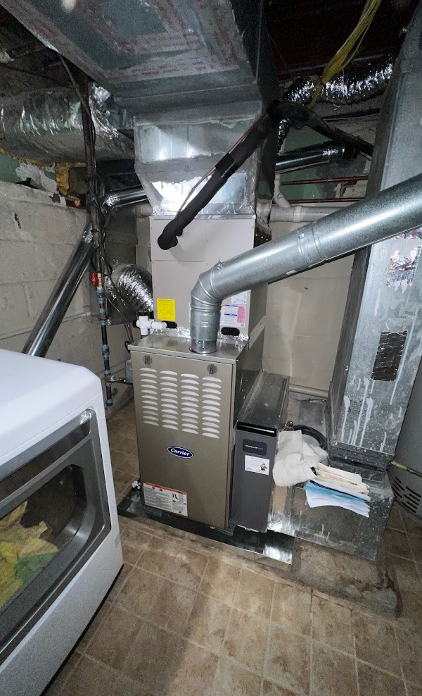 A gas furnace in a Northern Virginia basement with a metal exhaust flue pipe rising out of the top and the coil cabinet above it