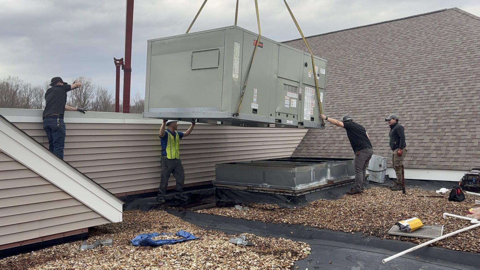 A SwiftPro crew on a Northern Virginia roof guiding a crane-lifted rooftop HVAC unit down onto its curb