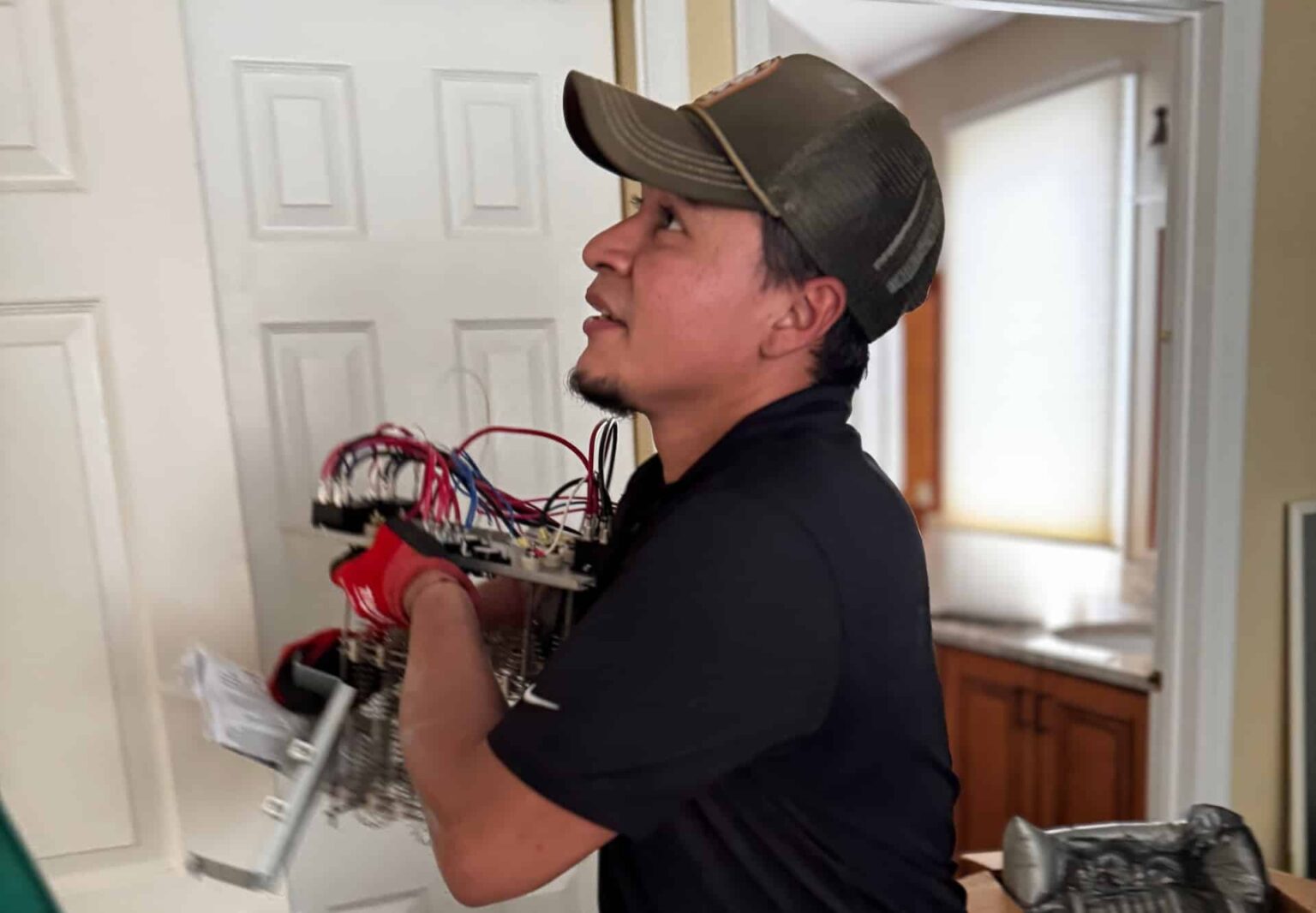 A SwiftPro technician holding an electric heat strip pulled from a heat pump air handler on a heating repair in Northern Virginia