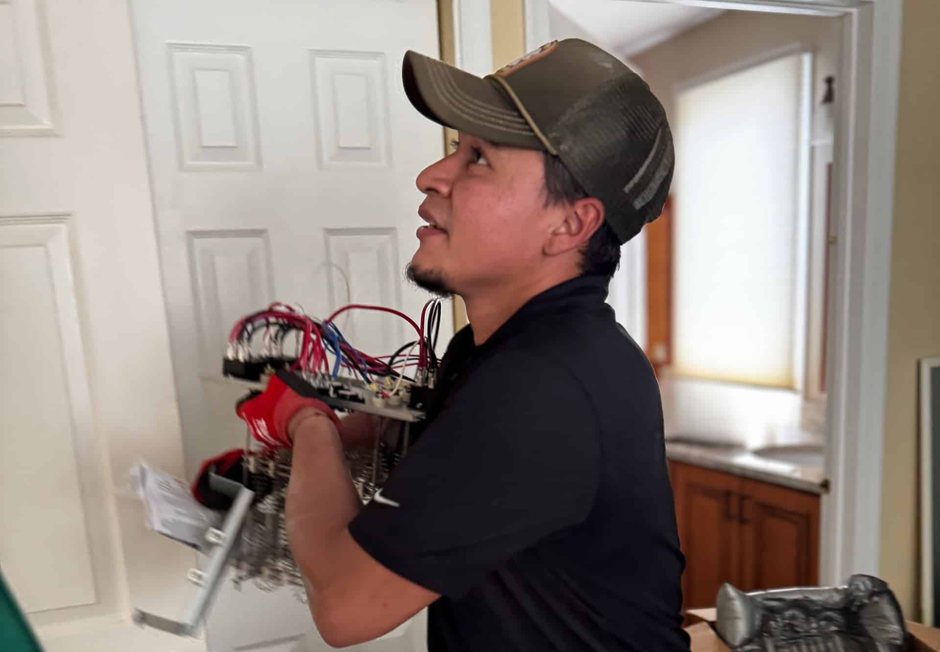 A SwiftPro technician carrying a furnace control board through a Northern Virginia home