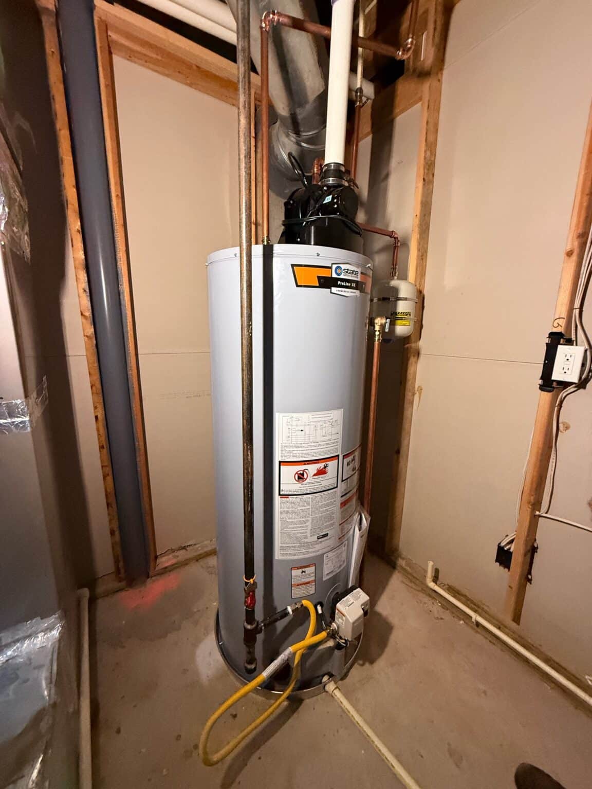 A new power vent gas water heater SwiftPro installed in a Chantilly, Virginia basement, the black exhaust fan and white vent pipe on top