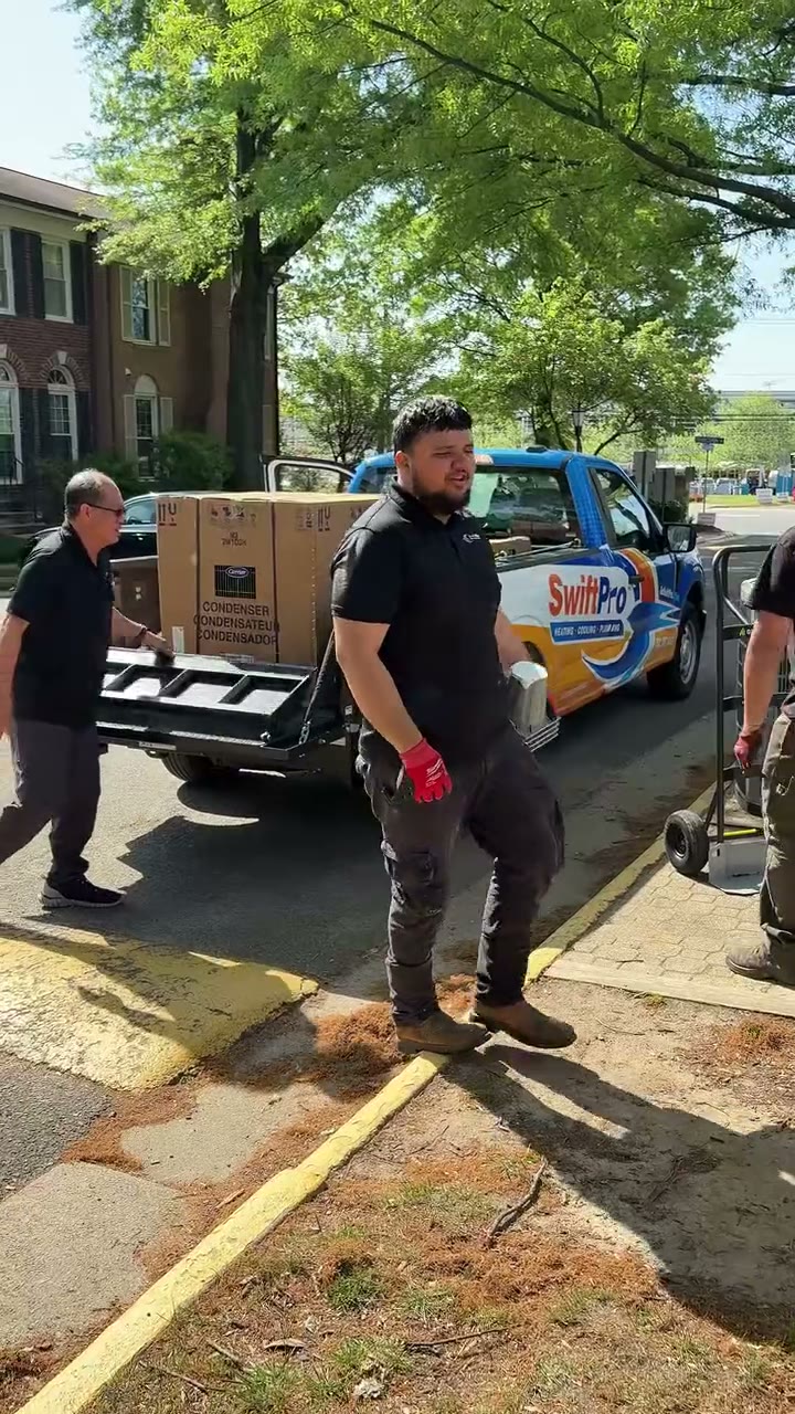 "Replacing an old A/C unit w/ SwiftPro": an old American Standard condenser is wheeled out of a townhouse backyard, a boxed new condenser comes off the truck liftgate, techs braze, wire the disconnect