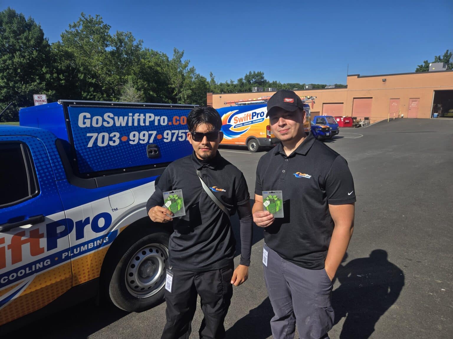 Two SwiftPro technicians in front of a wrapped SwiftPro truck in the lot of the SwiftPro shop in Chantilly, Virginia