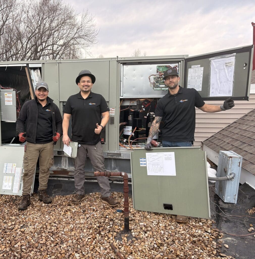 Three SwiftPro HVAC technicians on a commercial roof in Fairfax Station, Virginia, beside a new rooftop unit with its service panels open