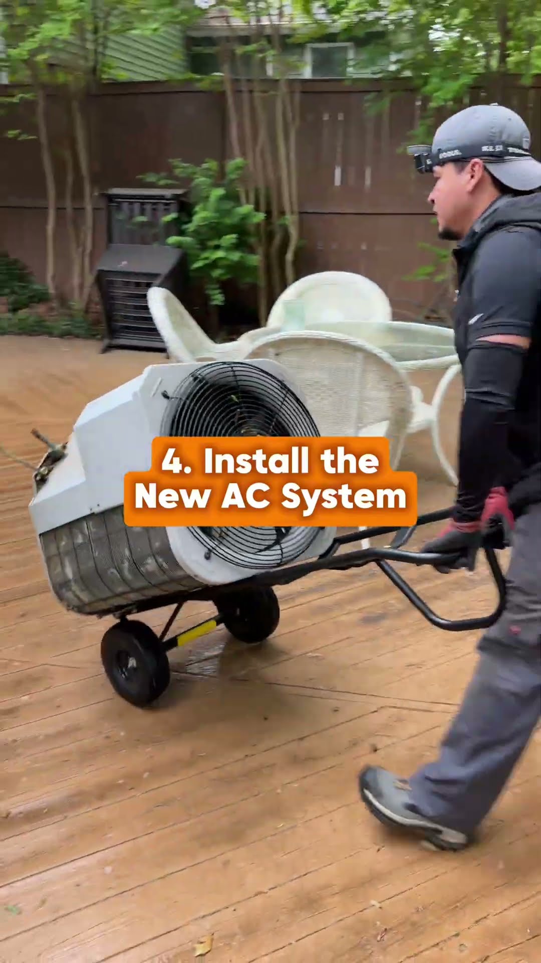 AC replacement walk-through: a tech in a navy hoodie hooks hoses to an old condenser beside a brick house, a tech wheels a new condenser on a dolly across a back deck with patio furniture, and a tech 