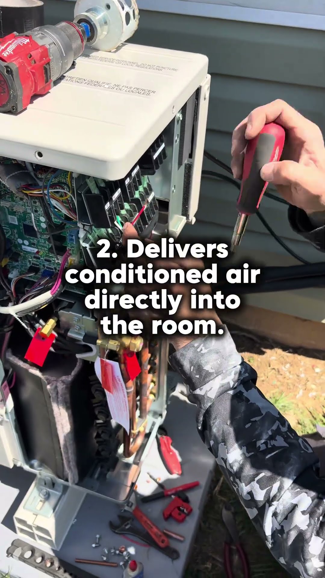 A mini-split outdoor unit opened up with a Milwaukee drill and screwdriver on top, showing the control board.
