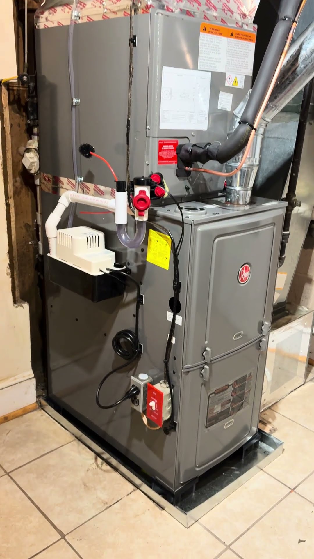 Two techs carry out an old furnace cabinet in an unfinished basement.